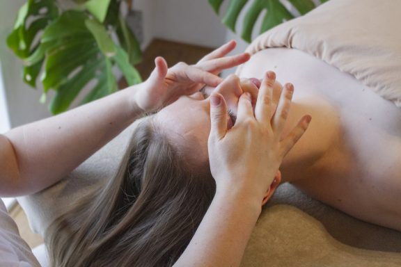 Een vrouw krijgt een postpartum massage. In haar gezicht worden haar shiatsu punten aangeraakt.